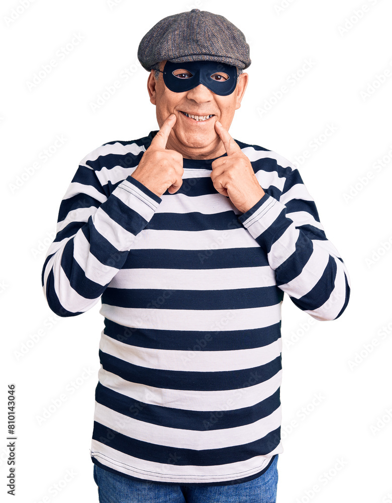 Wall mural Senior handsome man wearing burglar mask and t-shirt smiling with open mouth, fingers pointing and forcing cheerful smile