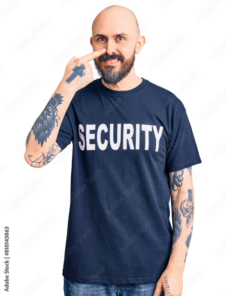 Sticker young handsome man wearing security t shirt pointing with hand finger to face and nose, smiling chee