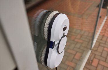 A robotic white Automotive tire is cleaning a glass window