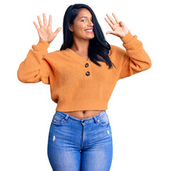 Hispanic woman with long hair wearing casual winter sweater showing and pointing up with fingers...