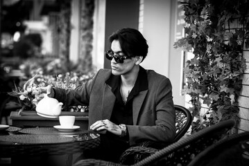 Handsome asian man in suit sits in cafe, bw. Grainy photo
