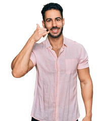 Hispanic man with beard wearing casual shirt smiling doing phone gesture with hand and fingers like talking on the telephone. communicating concepts.