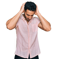 Hispanic man with beard wearing casual shirt suffering from headache desperate and stressed because pain and migraine. hands on head.