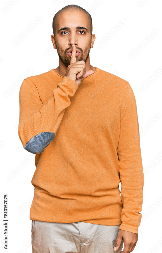 Wall mural Hispanic adult man wearing casual winter sweater asking to be quiet with finger on lips. silence and secret concept.