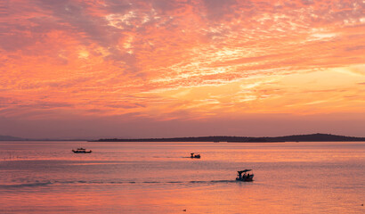 Fishermen's boats on a lake and the orange sunset