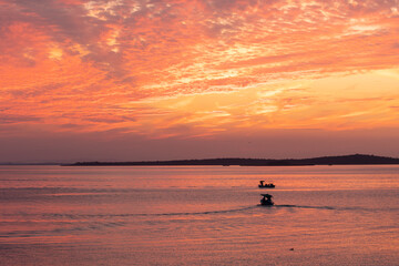 Two boats are sailing on the lake at the sunset