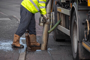 Gully sewer drain jet cleaning. MVC tanker truck operative uses suction pipe