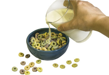 Pour milk from a glass into a bowl with breakfast cereals.