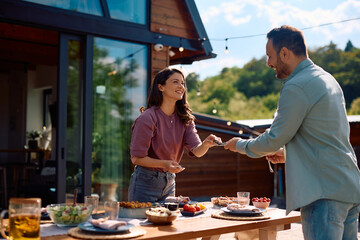 Happy couple setting dining table on  patio.