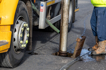 Gully sewer drain jet cleaning. MVC tanker truck operative uses suction pipe