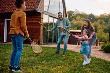 Happy family playing badminton in the backyard in spring day.