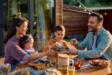 Happy family having dessert while eating at dining table on patio.