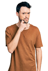Hispanic man with beard wearing casual t shirt thinking concentrated about doubt with finger on...