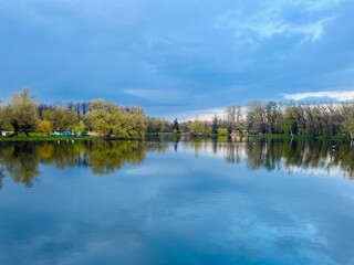 Pond in the park, evening time, trees reflection on the water surface