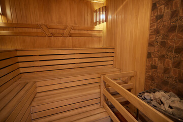A hardwood sauna with a plank ceiling, brick wall, and stairs