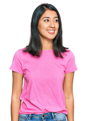 Fototapeta premium Beautiful asian young woman wearing casual pink t shirt looking away to side with smile on face, natural expression. laughing confident.