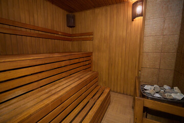 A hardwood sauna with a plank ceiling, brick wall, and stairs