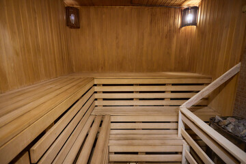 A hardwood sauna with a plank ceiling, brick wall, and stairs