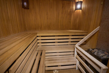 A hardwood sauna with a plank ceiling, brick wall, and stairs