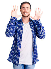 Young handsome caucasian man wearing casual clothes showing and pointing up with fingers number...