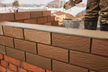professional construction worker laying bricks and building barbecue in industrial site. Detail of...