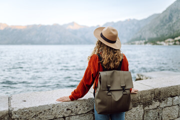Young woman with backpack near lake on wooded mountains background. Amazing landscape. Enjoying...