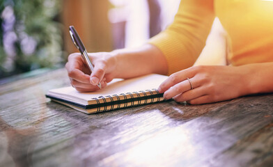 Woman, closeup and notebook for notes, schedule and planning on table in cafe with pen. Wife,...
