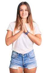 Fototapeta premium Beautiful caucasian woman wearing casual white tshirt praying with hands together asking for forgiveness smiling confident.