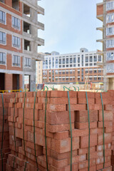 Stack of bricks on wooden pallet in front of building under construction