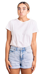 Obraz premium Young beautiful blonde woman wearing casual white tshirt puffing cheeks with funny face. mouth inflated with air, crazy expression.