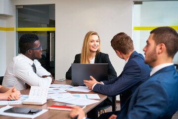 Multiracial team engages in corporate meeting, African, Caucasian business reps discuss projects with female team lead in modern office, showcasing gender diversity and multiethnic collaboration.
