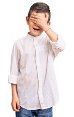 Fototapeta premium Cute blond kid wearing elegant shirt smiling and laughing with hand on face covering eyes for surprise. blind concept.