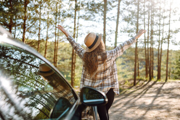 Young woman enjoying and having fun in their vacations outdoors leaning out car window. Summer trip.