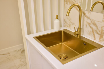 A gold faucet on a bathroom sink with a soap bottle
