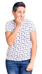 Young woman with short hair wearing casual clothes looking stressed and nervous with hands on mouth biting nails. anxiety problem.