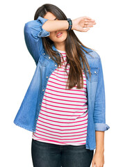 Young brunette woman wearing casual clothes covering eyes with arm, looking serious and sad. sightless, hiding and rejection concept