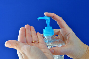 Person's hands applying washless hand sanitizer gel to help stop the spread of germs. blue...