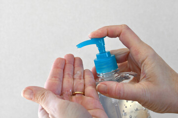 Person's hands applying washless hand sanitizer gel to help stop the spread of germs. white...