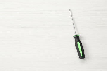 Screwdriver with black handle on white wooden table, top view. Space for text