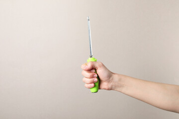 Woman holding screwdriver on grey background, closeup