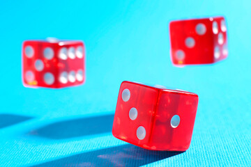 Three red game dices falling on light blue background, closeup