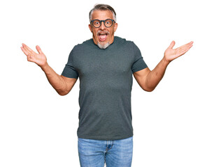 Fototapeta premium Middle age grey-haired man wearing casual clothes and glasses celebrating victory with happy smile and winner expression with raised hands