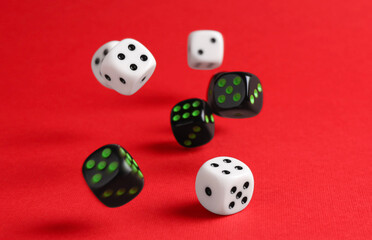 Many color game dices falling on red background. Space for text