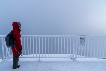 Turystka z plecakiem na szlaku w górach. Ubrana w czerwona kurtke zimowa z kapturem oraz ciemne...