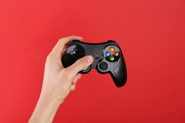 Man using wireless game controller on red background, closeup