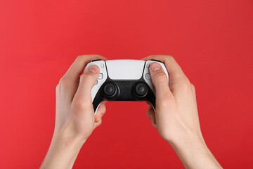 Man using wireless game controller on red background, closeup