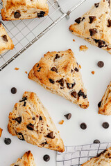View from above of gourmet chocolate chip scones on white kitchen counter with cooling rack, recipe styling concept, Generative AI