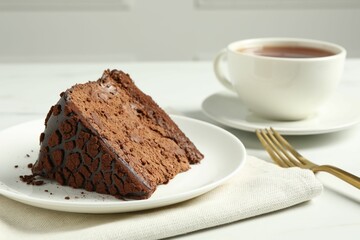 Piece of delicious chocolate truffle cake on white table, closeup