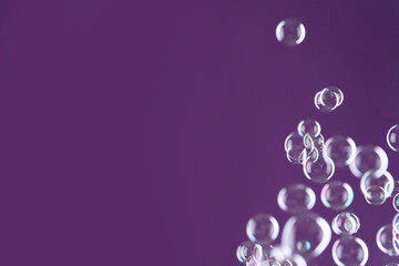 Beautiful transparent soap bubbles on purple background, space for text