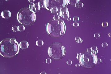 Beautiful transparent soap bubbles on purple background
